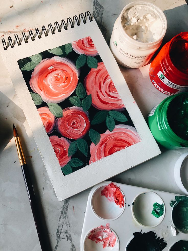 an artist's work is being displayed on a table with paints and brushes in front of it