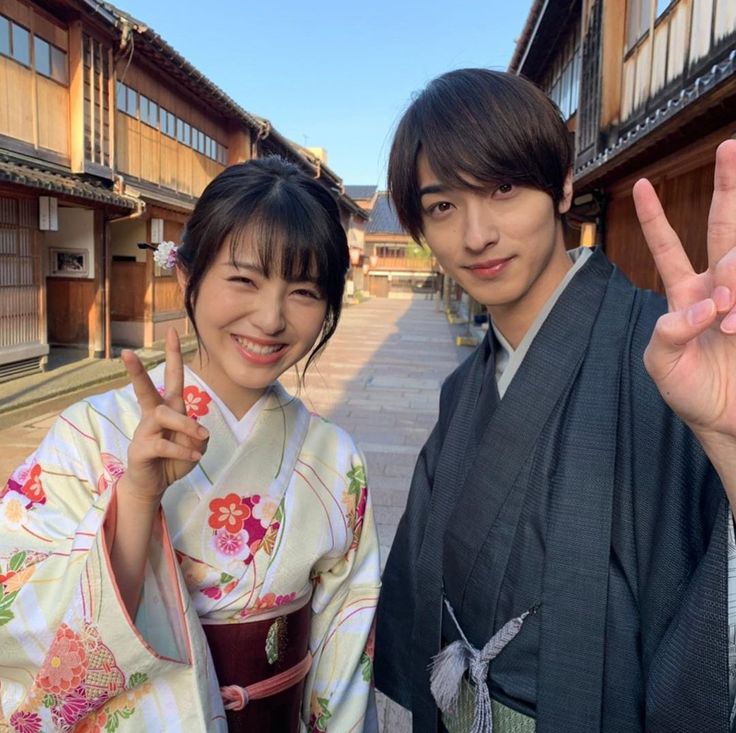 two people in kimonos posing for the camera with their peace sign and fingers up