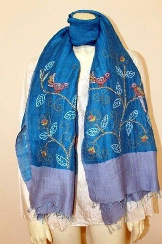 a mannequin wearing a blue scarf with flowers and leaves on the bottom,