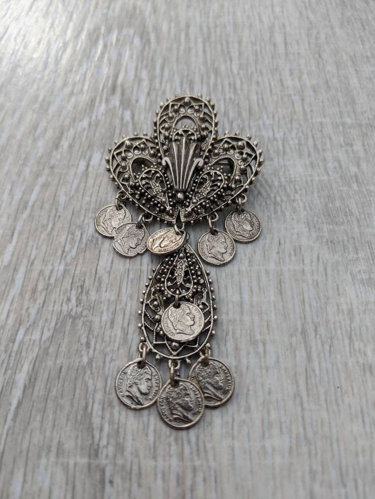 "This gorgeous Arthur Pepper brooch exhibits all the characteristics of the Midcentury Etruscan Revival period in jewelry design. It features a large, incredibly intricate silver tone fleur-de-lis, its openwork lines crisscrossed with repeated geometric patterns and dotted with tiny spheres. Both the classic French three-pronged lily and the teardrop shaped framework that dangles below it are adorned with replicas of Emperor Napoleon coins. The early 19th Century francs show the ruler's bust in Vintage Ceremonial Pendant Brooches, Vintage Ceremonial Pendant Brooch, Vintage Pendant Brooches For Ceremonial Occasions, Emperor Napoleon, Hat Brooch, Enamel Flower, Vintage Costume Jewelry, White Enamel, Art Jewelry