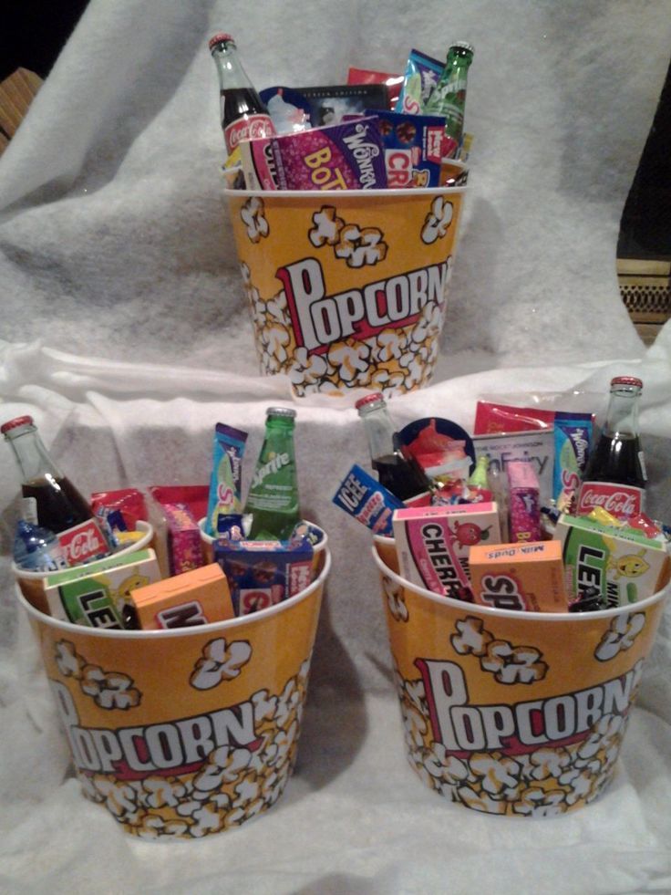 three buckets filled with different types of snacks and drinks on a white table cloth