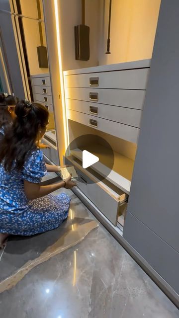 a woman kneeling down in front of a cabinet with drawers on the side and an oven door open