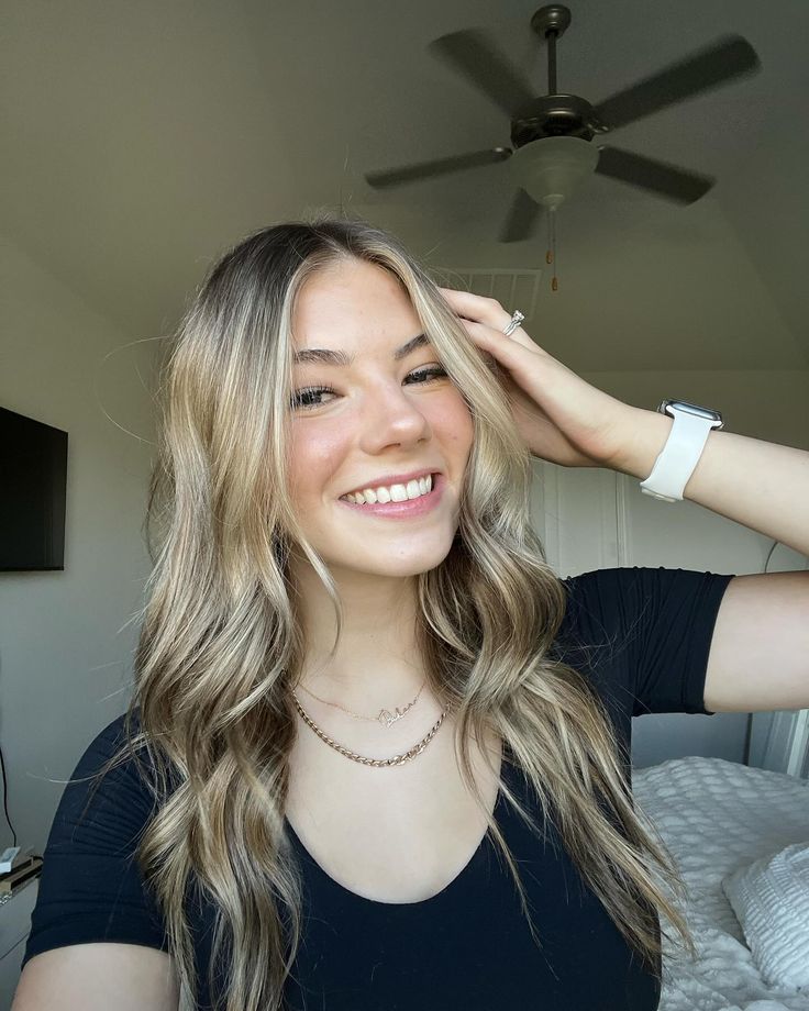 a woman is smiling while holding her hair