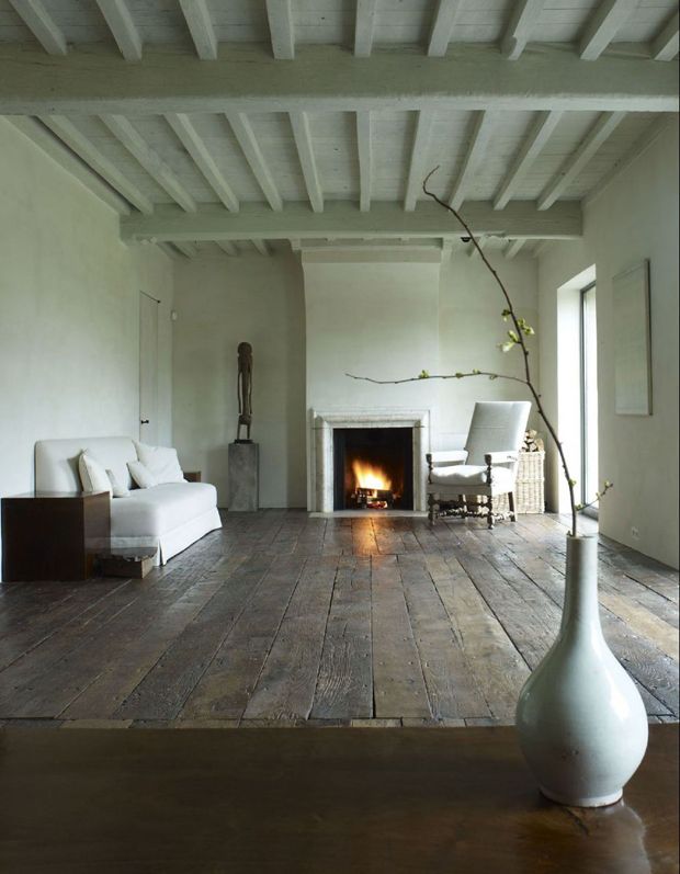 a living room filled with furniture and a fire place next to a white couch on top of a hard wood floor