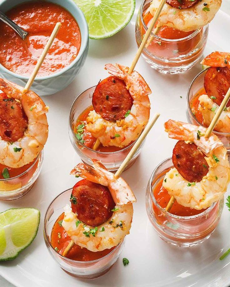 shrimp skewers with tomato sauce and lime wedges