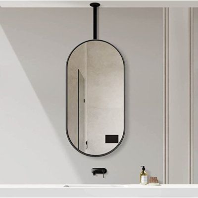 an oval mirror hanging on the wall next to a sink in a room with white walls