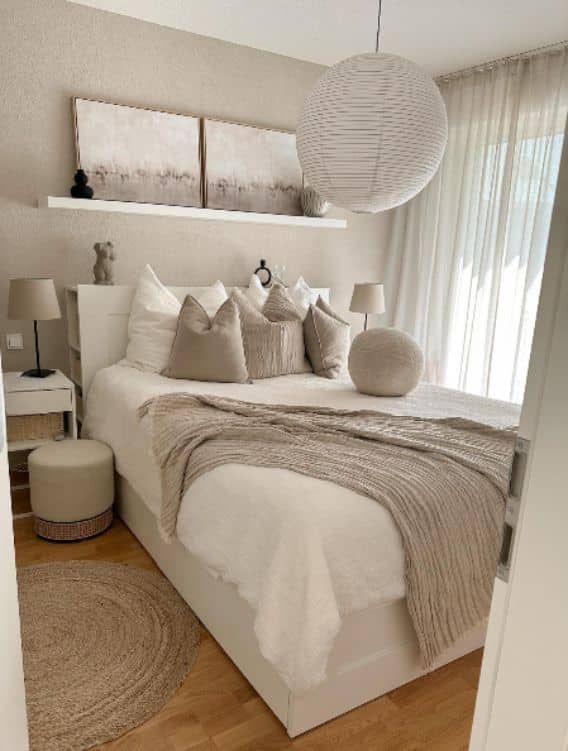 a white bed sitting in a bedroom on top of a hard wood floor next to a window