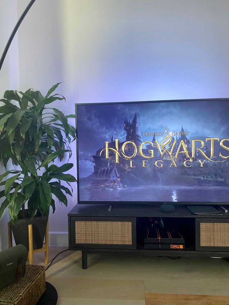 the hogwarts logo is displayed on a large screen television in a living room