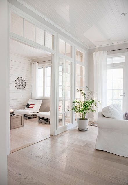 an open living room with white furniture and large windows on the side of the wall