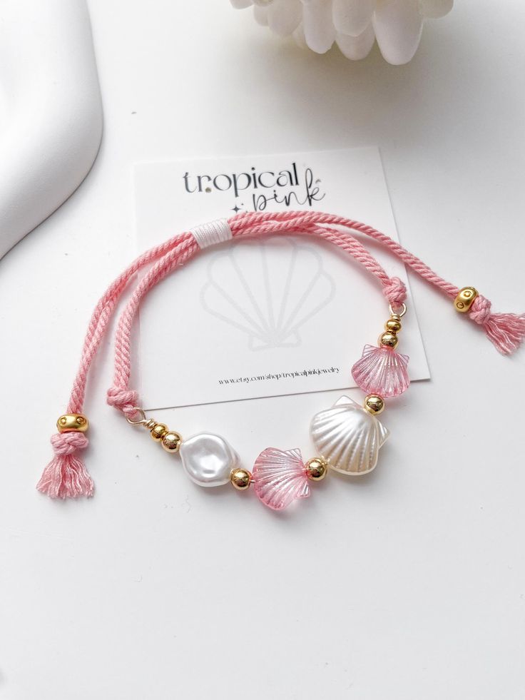 🐚 Shellebrate summer with these beautiful shell bracelets! 😎 All of our bracelets are handmade with high quality materials. The listing is for one bracelet, images showing more than one are an example of how they would look stacked with other bracelets. ITEM DETAILS  🐠 Acrylic clam beads 🐠 Sturdy nylon cord 🐠 Gold plated beads CARE TIPS 🤍 Keep your jewelry dry and away from perfumes or any harsh chemicals 🤍 Store your jewelry separately, and avoid wearing it if you are going to work out. Thank you so much for visiting my shop! 💖 Discover more jewelry by Tropical Pink at: https://www.etsy.com/shop/Tropicalpink Follow me on instagram for behind the scenes: @tropicalpink_jewelry Cheap Pink Pearl Bracelet For Beach, Cheap Adjustable Shell Bracelets, Tropical Bracelets, Beach Jewelry Aesthetic, Bracelet Images, Seashell Bracelet, Bracelet Inspo, Coastal Aesthetic, Aesthetic Gift