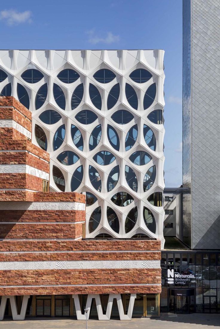 the building has many circular windows and is made out of red bricks with white arches