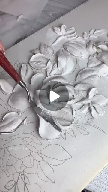 someone is using a large knife to paint a flower on a piece of white paper