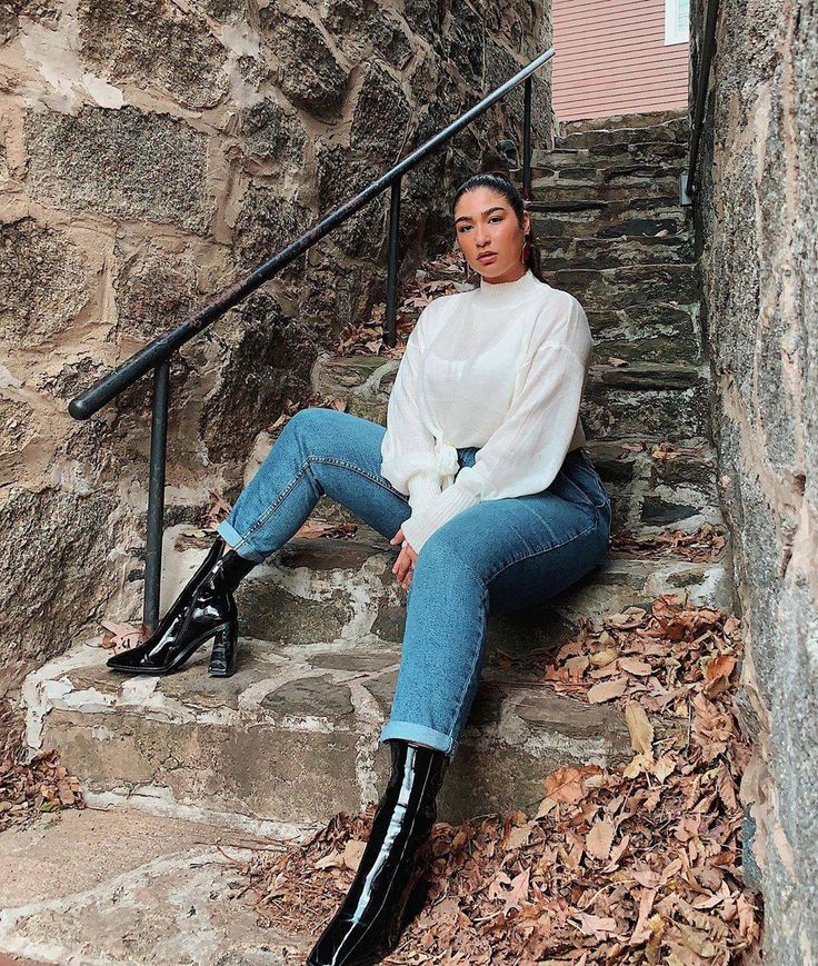 a woman is sitting on some steps with her legs crossed and wearing high heeled boots