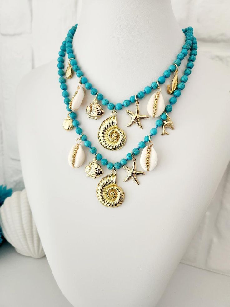 Beautiful turquoise howlite bead necklace adorned with a variety of exquisite beach-inspired charms. This stunning piece captures the essence of the sea, bringing a touch of elegance and sophistication to any outfit. The necklace is made of knotted stones and all the charms are 18k gold plated. It is a super trendy design, Whether you're spending a day at the beach, going out to dinner, or enjoying a casual outing with friends, it's a versatile addition to your jewelry collection. A fun way to m Ocean-inspired Pendant Necklace, Handmade Ocean-inspired Blue Necklaces, Ocean-inspired Turquoise Jewelry For Vacation, Turquoise Ocean-inspired Jewelry For Vacation, Handmade Ocean-inspired Ocean Color Necklaces, Turquoise Jewelry With Starfish Charm For Vacation, Handmade Ocean Color Necklaces For Jewelry Making, Ocean-inspired Green Necklaces For Beach, Green Ocean-inspired Necklaces For The Beach