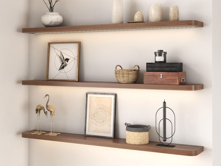 some shelves with pictures, vases and other items on them in a room that has white walls