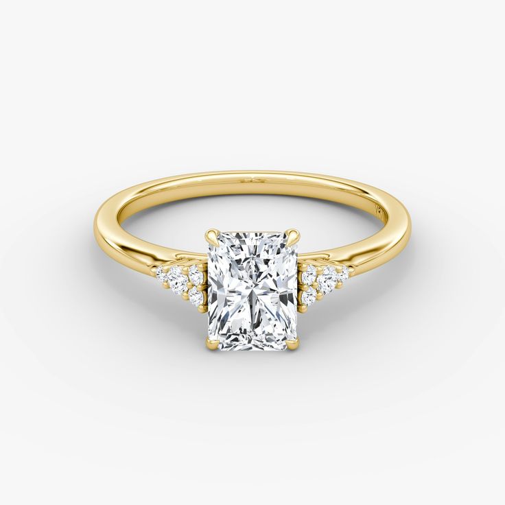 a yellow gold engagement ring with a princess cut diamond in the center and side stones