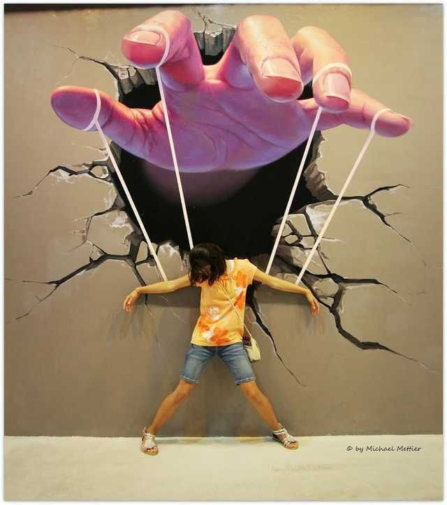 a girl standing in front of a giant hand painted on the wall