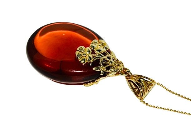 Pendant handcrafted  of sterling silver covered 14ct. gold and natural Baltic amber.Amazing cherry amber stone with a floral gold hanger.This fabulous jeweller adds colour for everyday and evening outfit. Amber stone created by nature over 25 millions years ego, amber attracts good luck, dissolves negative energy ,balances emotions. Care Instructions: To maintain your jewellery, wipe gently with a cotton cloth that is soft and clean. Do not soak in water. Avoid contact with soaps, detergents, pe Formal Baltic Amber Pendant Jewelry, Cabochon Baltic Amber Necklace As Gift, Elegant Gold Baltic Amber Necklace, Elegant Baltic Amber Necklaces For Gifts, Baltic Amber Cabochon Necklace For Gift, Amber Hallmarked Necklaces For Gifts, Elegant Baltic Amber Round Pendant Jewelry, Baltic Amber Pendant Necklace As Gift, Baltic Amber Pendant Jewelry Gift