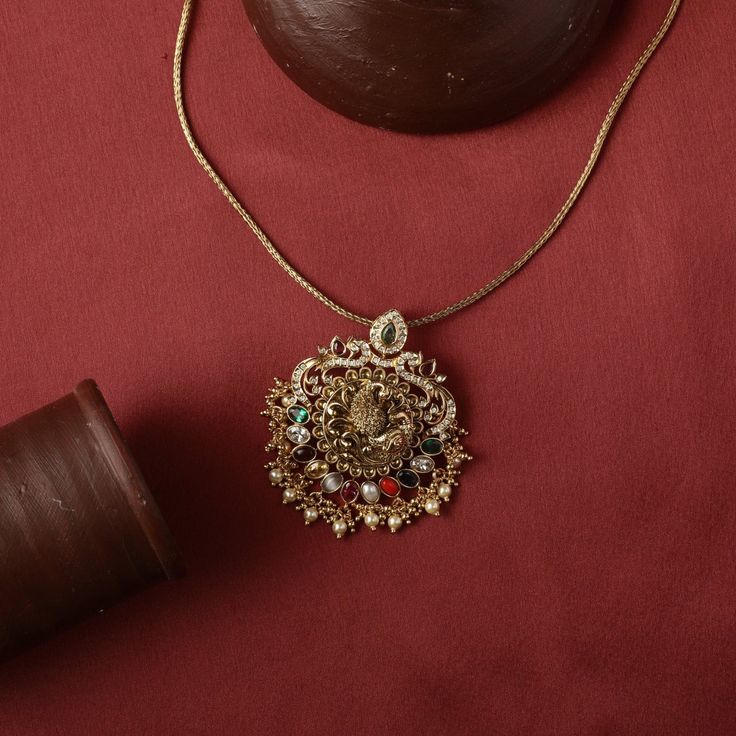 Description : This magnificent antique nakshi silver pendant is handcrafted on hallmark 925 silver in temple theme. The pendant is intricately crafted with a peacock motif sitting on the center surrounded by Navaratna stones. Expertly crafted by skilled artisans, this set is perfect for any special occasion. Product Information : Materials used : 925 Silver With Antique Gold Plating Stones: Semi precious stones Length: Pendant with chain-26.5cm Findings: Hook and links Meenakari Temple Necklace Pendant For Puja, Meenakari Pendant Temple Necklace For Puja, Temple Style Kundan Necklace With Pendant Stone Setting, Temple Style Kundan Pendant Necklace With Stone Setting, Temple Jewelry Style Kundan Necklace With Pendant, Temple Style Kundan Pendant Necklace, Temple Style Necklace With Stone Setting As A Gift, Spiritual Kundan Pendant Necklace For Celebration, Temple Jewelry Necklace With Stone Setting As Gift