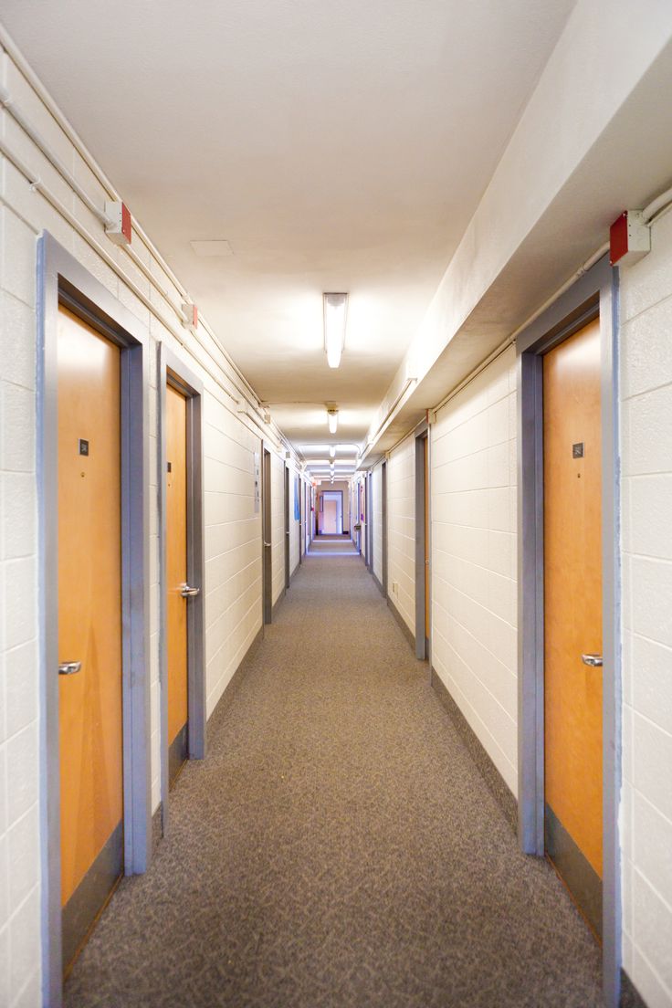 an empty hallway with doors leading to another room on either side and light above the door