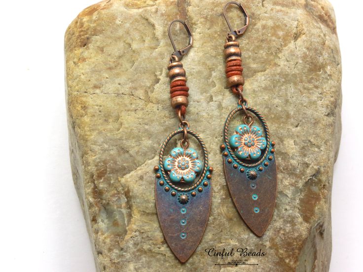 These captivating earrings showcase a unique blend of textures and colors, perfect for adding a touch of bohemian flair to your ensemble. The focal point is a stunning copper tribal pendant, adorned with a rich turquoise patina. Suspended within the pendant is a delicate Czech glass turquoise wild rose flower, adding a hint of romantic charm. The earrings are further enhanced by the addition of spacer beads and decorative leather barrel knots, lending a rustic and handcrafted feel. Choose from 4 different earwire options to find the perfect fit for your style. 𝐋𝐄𝐍𝐆𝐓𝐇: 3 1/2" with lever back earwires. Kidney wires will add about 1". 𝐖𝐈𝐃𝐓𝐇: 3/4" 𝐖𝐄𝐈𝐆𝐇𝐓: Each earring weighs 6.50 grams. A nickel weighs 5 grams. All jewelry is packaged ready for gift giving. Each item comes in Bohemian Brown Flower Jewelry, Bohemian Metal Drop Flower Earrings, Bohemian Metal Flower Drop Earrings, Adjustable Bohemian Patina Earrings, Adjustable Bohemian Drop Flower Earrings, Adjustable Bohemian Flower Earrings, Rustic Patina Jewelry For Festival, Turquoise Bohemian Earrings With Ear Wire, Bohemian Turquoise Earrings With Ear Wire