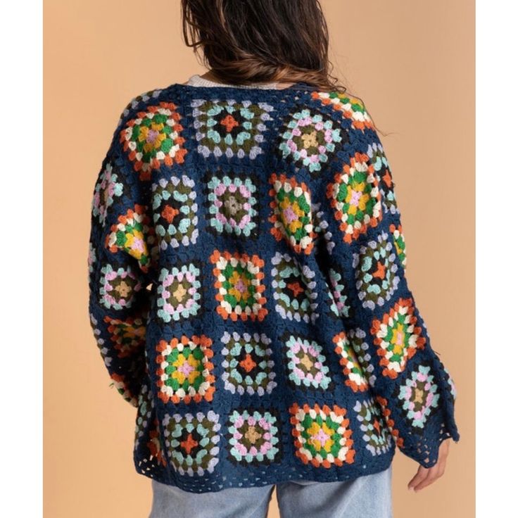 a woman wearing a blue crocheted sweater with multicolored squares on it