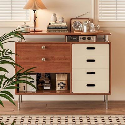 a dresser with drawers and a lamp on top of it next to a potted plant