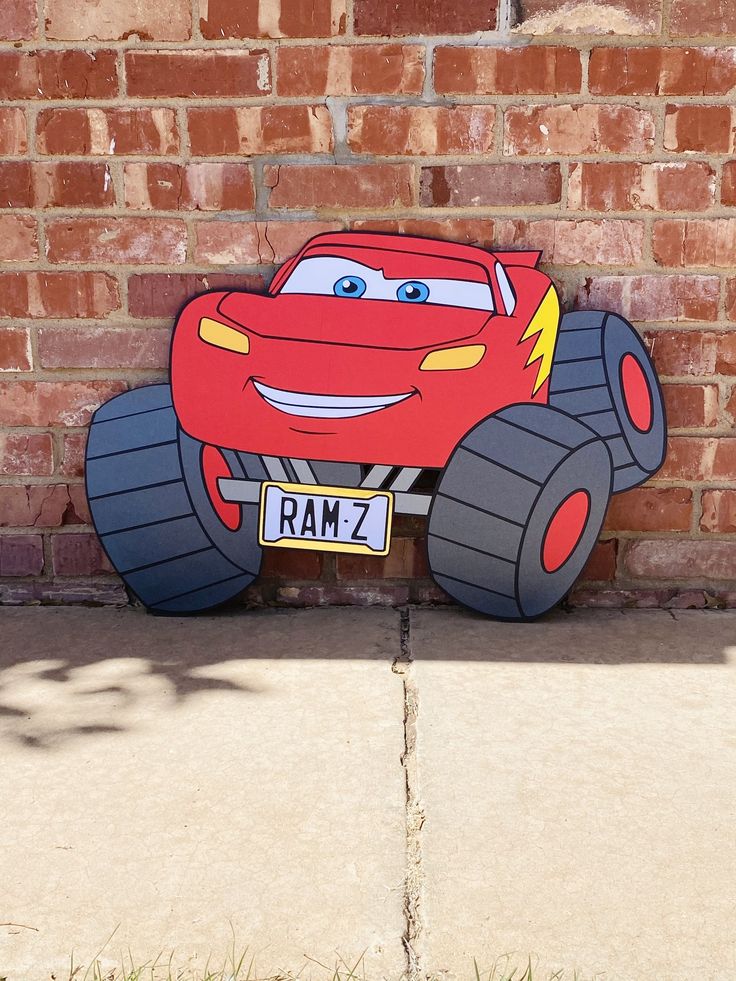 a cartoon character is painted on the side of a brick wall with grass in front of it