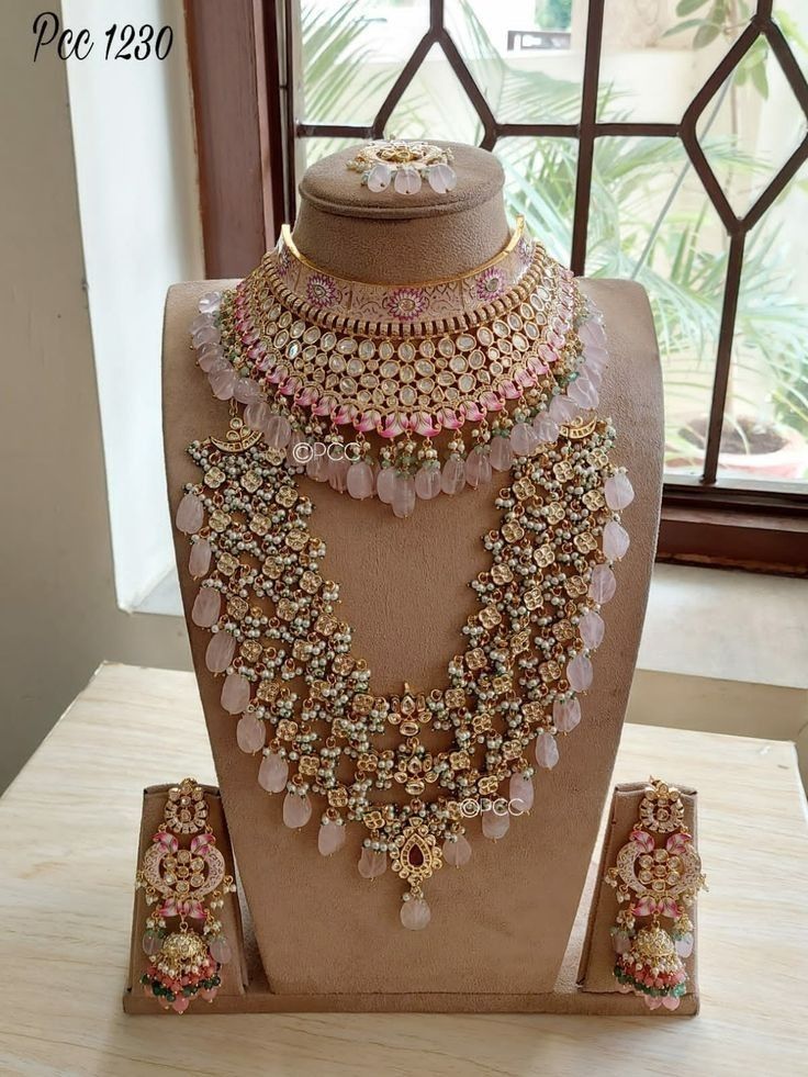 an elaborate necklace and earring set on display in front of a window with glass panes