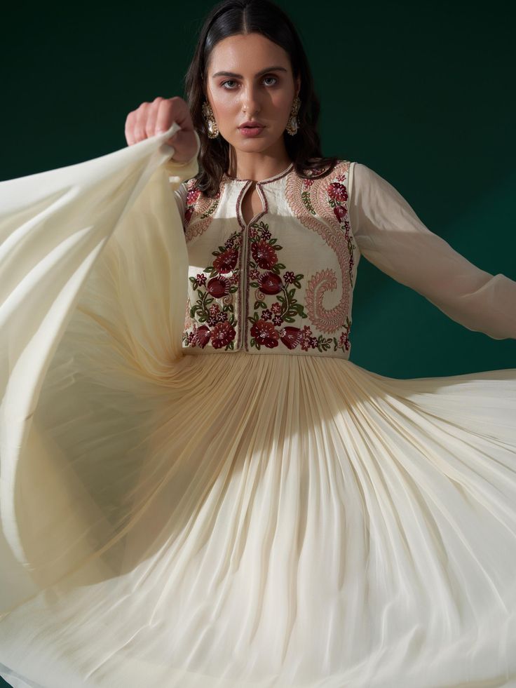 A three-piece Cream Maroon Koti Jacket Anarkali set from the Suruchi Parakh collection. The solid cream full sleeves Anarkali is paired with a paisley thread embroidered koti jacket in floral work. The pleated style anarkali has a back hook and zip opening. There is sequin, bead, pearl and thread work on the koti jacket. The cream color with floral embroidery, and floral butta motifs enhances the graceful, anarkali set. The outfit is completed with a beautiful maroon ombre dupatta with pearl pip Fitted Anarkali Salwar Kameez With Intricate Embroidery, Fitted Anarkali Churidar With Intricate Embroidery, Fitted Maxi Salwar Kameez With Floral Embroidery, Fitted Floral Embroidered Maxi Salwar Kameez, Fitted Anarkali Set With Intricate Embroidery In Georgette, Beige Semi-stitched Anarkali Choli, Beige Anarkali Semi-stitched Choli, Floor-length Fitted Churidar With Floral Embroidery, Fitted Floor-length Churidar With Floral Embroidery