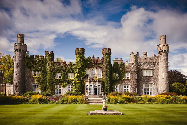 an old castle with ivy growing all over it's walls and windows, surrounded by lush green grass