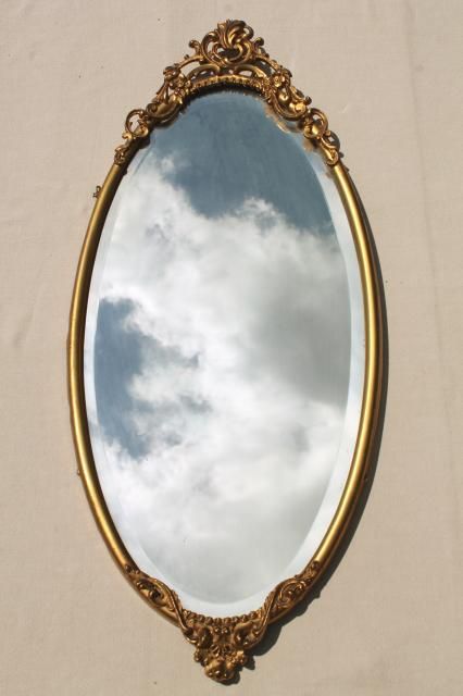 a mirror that is sitting on the side of a wall with clouds reflected in it