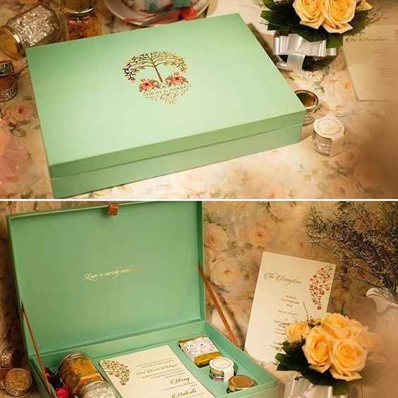 an open box with two cards inside and flowers on the table next to each other