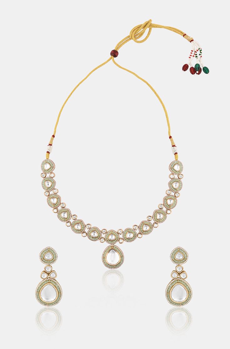 Introducing a mesmerizing long Kundan necklace adorned with opulent meena-inspired details and oversized Kundan stones, accompanied by matching earrings. Crafted from mixed metals with lavish 22kt gold plating, this set radiates timeless elegance and sophistication, perfect for making a grand statement. Finish: 22KT Gold Plating Material: Brass, Kundan & Mint Green Beads Color: White, Green Size: Free Size, Adjustable Closure Type: Draw String Box Contains: 1 Necklace, 1 Pair of Earrings Festive Gold Bridal Necklace With Gota Work, Gold Bridal Necklace With Gota Work For Celebration, Festive Elegant Necklaces With Gota Work, Elegant Festive Gota Work Necklaces, Gold Jewelry Sets With Gota Work For Festive Occasions, Gold Necklace With Mirror Work, Elegant Temple Necklace With Gota Work For Diwali, Gold Necklaces With Mirror Work For Diwali, Gold Necklace With Mirror Work For Diwali