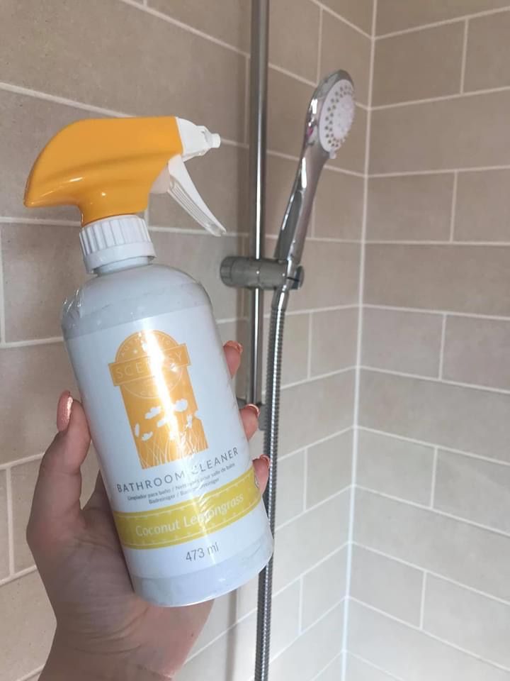 a person holding a spray bottle in front of a shower