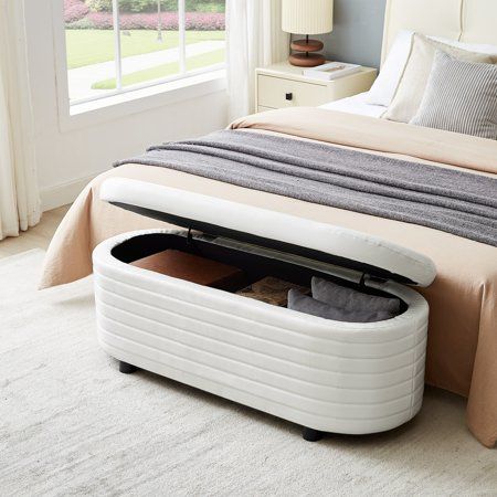 a bed with an ottoman underneath it in a bedroom