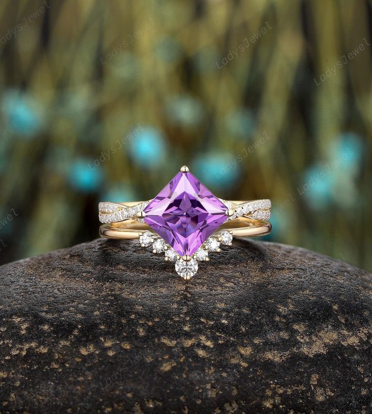 a ring with an amethorate and diamonds on it sitting on top of a rock