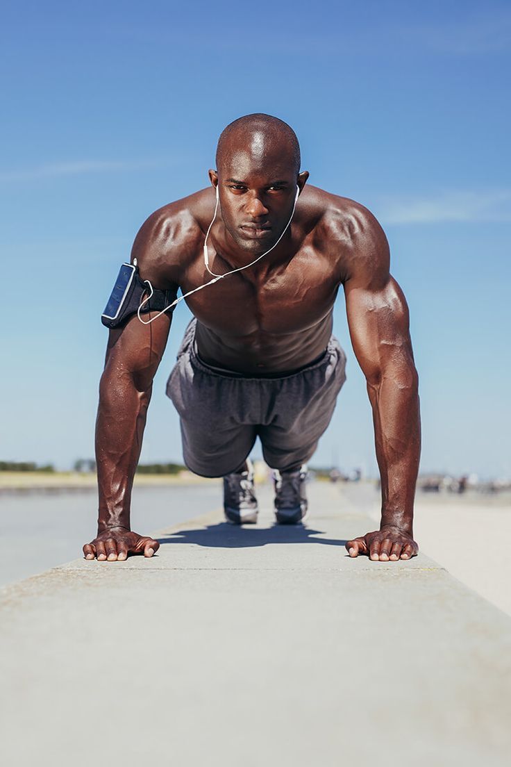 a man doing push ups on the beach with headphones in his ears and an mp3 player attached to his ear