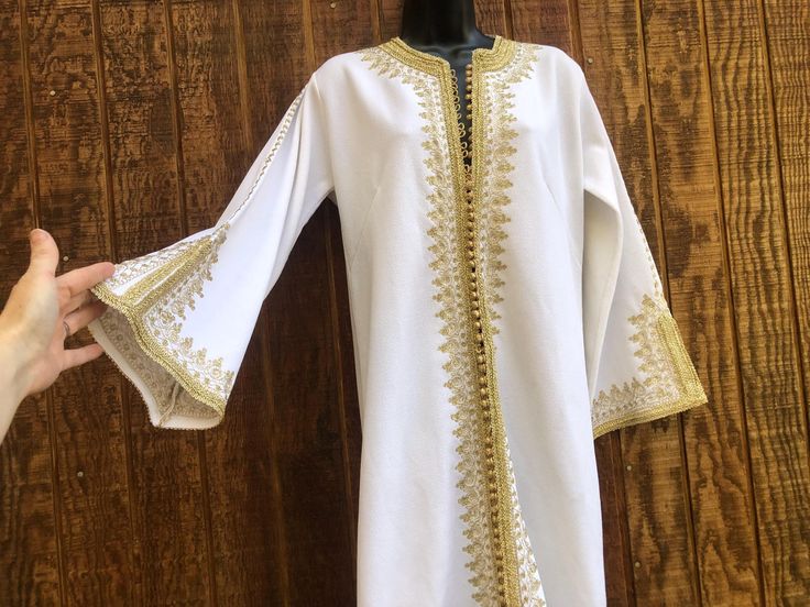 White with gold embroidery Vintage long dress. No tags - estimated medium to large - please see measurements. Condition - has some stains in back - see last photo.   Measurements taken across front laid flat Size: Estimated medium to large Bust: 18" Waist: 19" hips: 21" Length (shoulder to hem): 53" White Ceremonial Dress With Zari Work, Ceremonial White Dress With Zari Work, Festive White Dress With Gold Embroidery, Gold Long Sleeve Thobe For Festive Occasions, Festive Gold Long Sleeve Thobe, Gold Embroidered Thobe For Festivals, Gold Dress With Chikankari Embroidery For Eid, White Dress With Gold Embroidery For Eid, Gold Chikankari Embroidery Dress For Eid