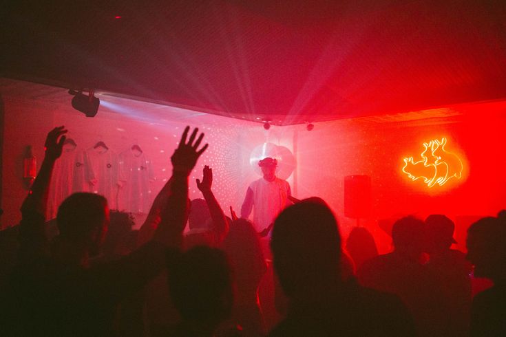 a group of people at a party with their hands up in front of the crowd