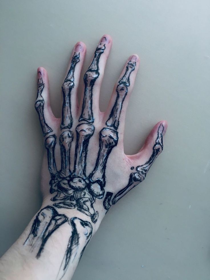 a person's hand with black and white ink on it, showing the skeleton hands