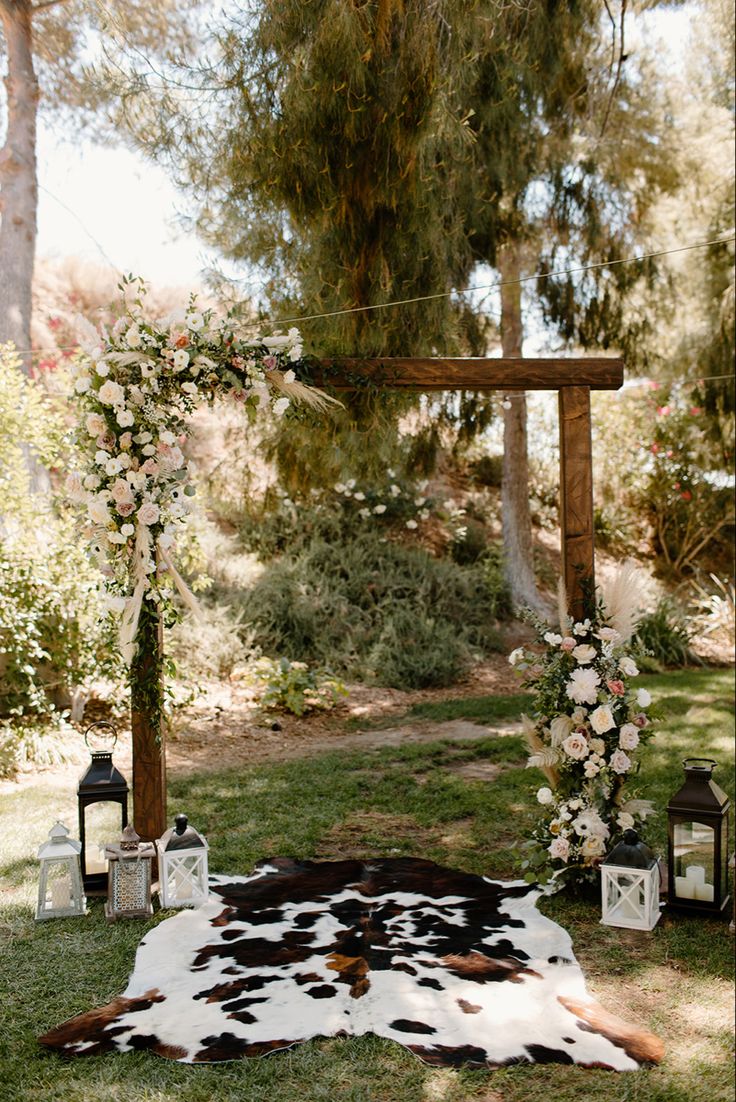 a cow skin rug on the ground with flowers and lanterns in front of an arch