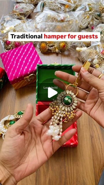 two hands are holding jewelry in front of a pile of other items on the floor