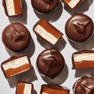 chocolates with white and brown frosting are arranged on a table