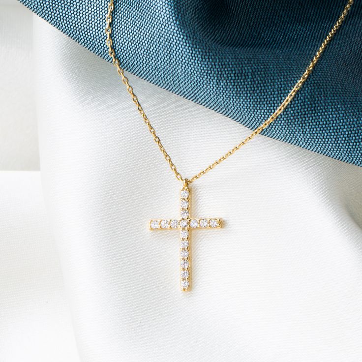 Experience the harmonious blend of tradition and elegance with our 14K Solid Gold Cross Necklace. This finely handcrafted piece features a petite cross pendant, measuring 7 mm wide and 11 mm tall, adorned with a singular cubic zirconia gemstone that captures the light and signifies purity. The skinny cable chain, available in lengths from 14 to 20 inches, provides a customizable fit for diverse preferences and comfort. Key Features: Refined Symbolism: Delicate cross pendant design for a modest e Cubic Zirconia Cross Necklace For Gift, Fine Jewelry Cubic Zirconia Cross Necklace, Brilliant Cut Cubic Zirconia Cross Necklace As Gift, Classic Cubic Zirconia Cross Necklace, Yellow Gold Cubic Zirconia Cross Necklace, Brilliant Cut Crucifix Necklaces For Gifts, Brilliant Cut Crucifix Necklaces As Gift, Brilliant Cut Cross Necklace As Gift, Brilliant Cut Crucifix Necklace For Gift