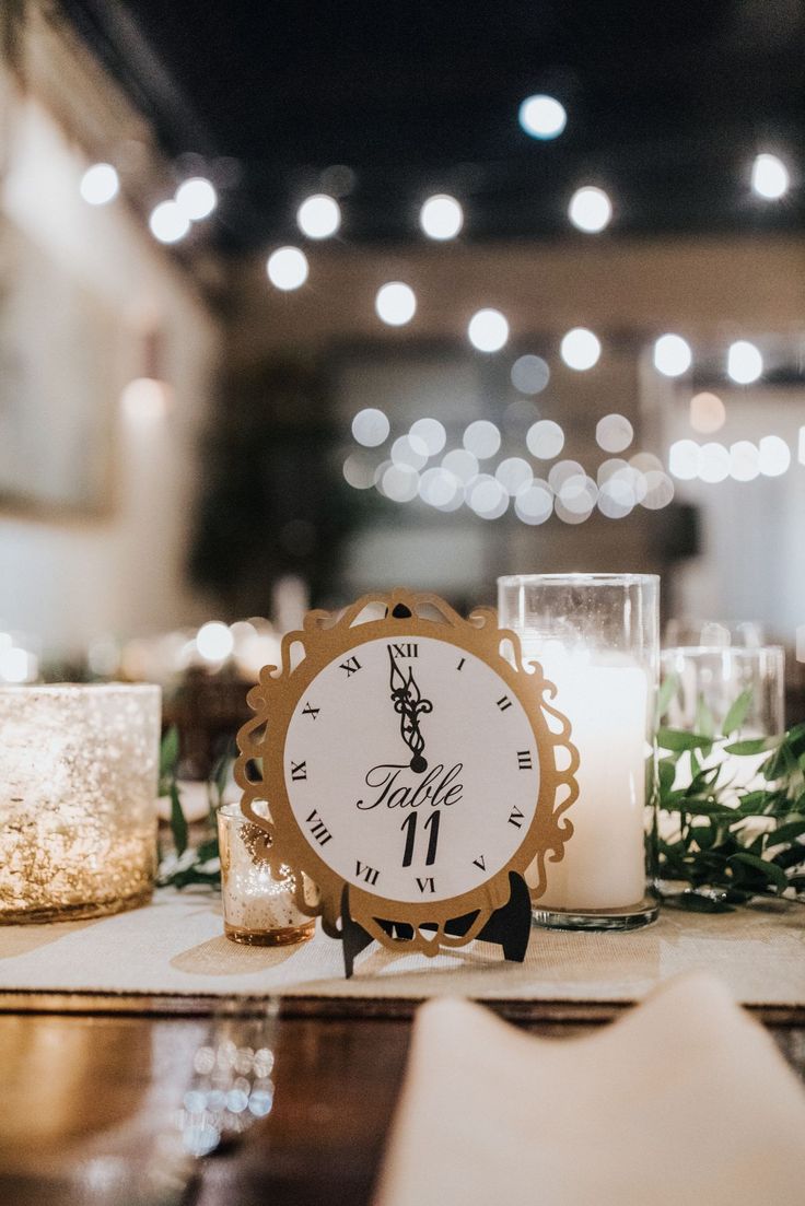 a clock sitting on top of a table next to a candle