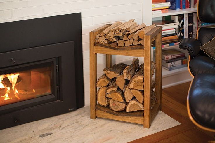 a fire place with logs stacked on it and a chair next to it in front of the fireplace