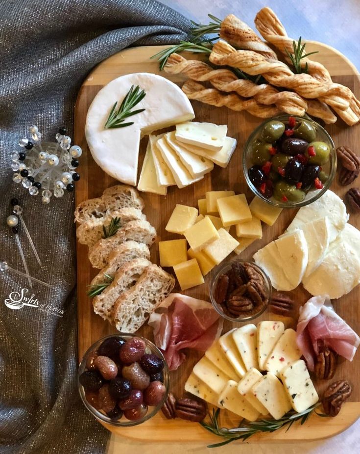 a cheese board with roasted grapes, olives, bread and crackers on it