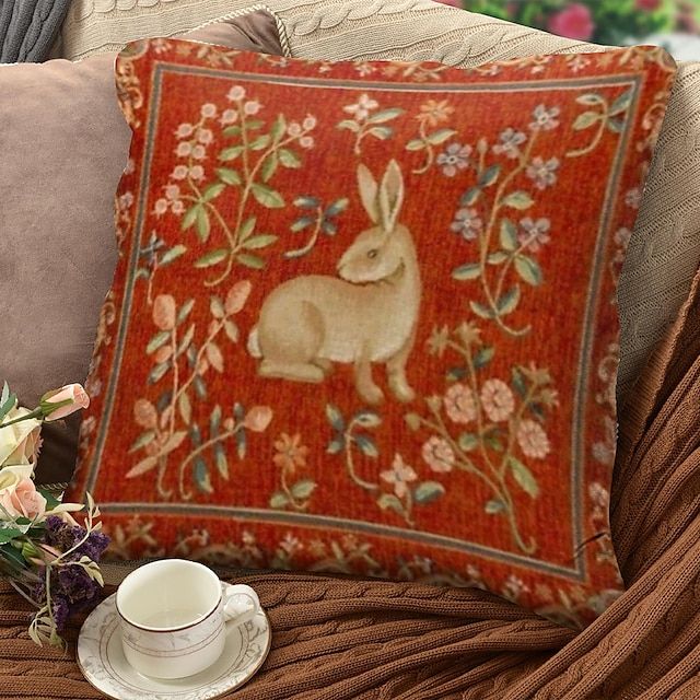 a decorative pillow with a rabbit on it next to a cup and saucer