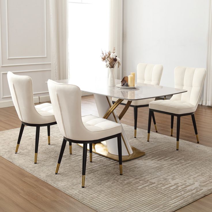 a dining room table with white chairs and a rug on the floor in front of it